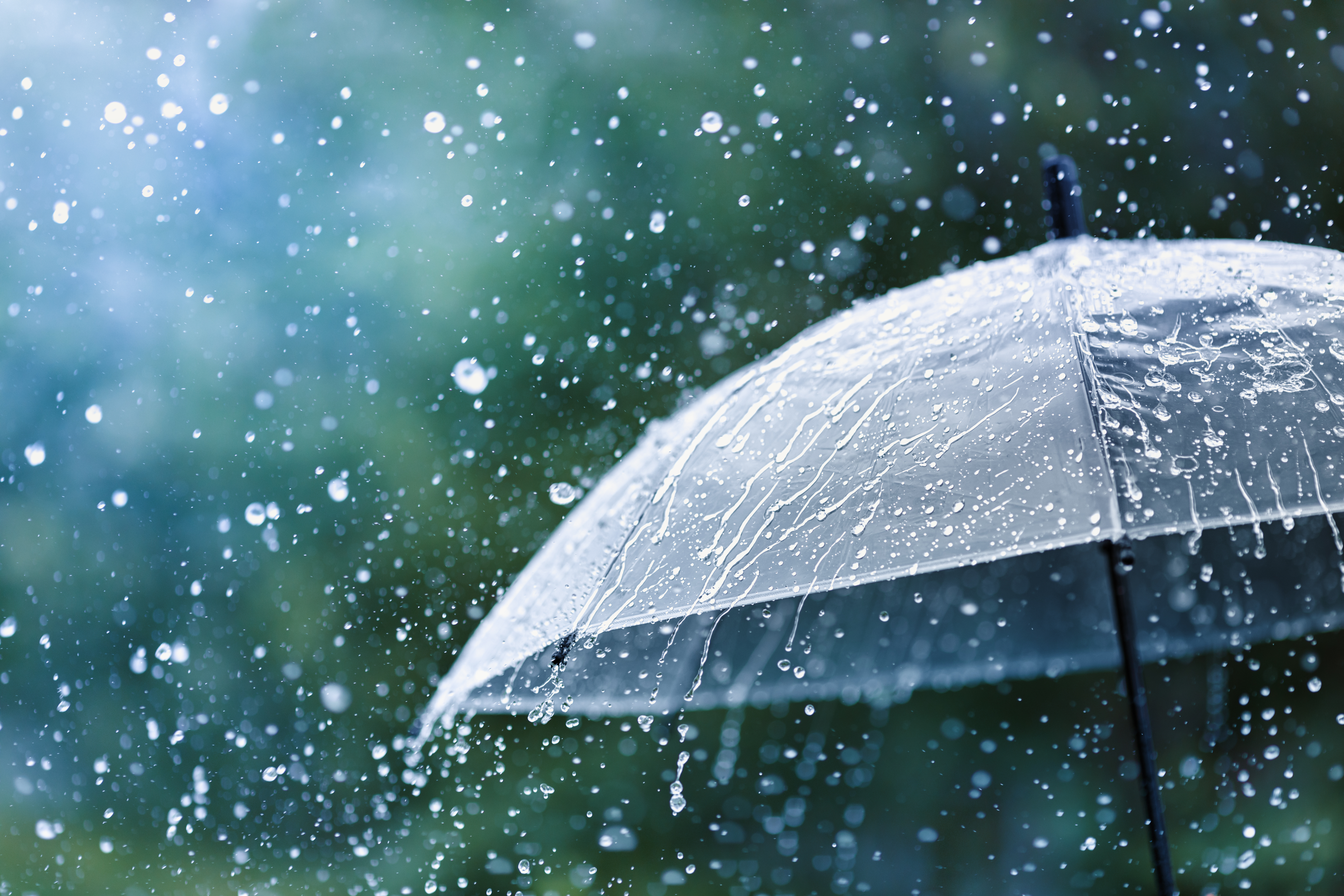 Transparent umbrella under rain against water drops splash background. Rainy weather concept.